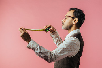 Portrait of a tailor looking down at fabric measure, isolated on pink studio background