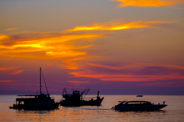 three boat on the sea at sunset