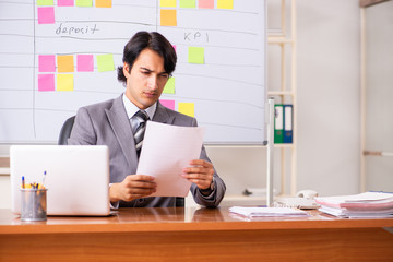 Young handsome employee working in the office