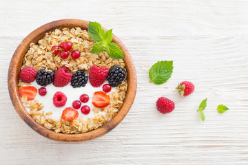 granola with berries on white wooden background