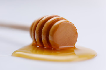 Wooden spoon with a drop of delicious liquid honey on a white background. Close-up.