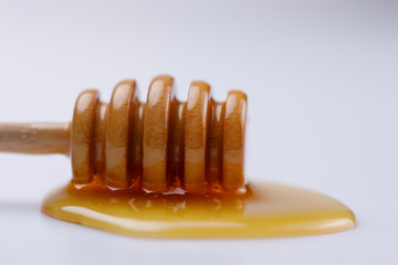 Wooden spoon stick with a drop of delicious honey on a white background. Close-up.