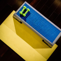 Set of fitness accessories: step platform, yoga mat and dumbbells