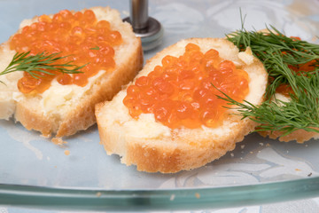 two sandwiches with caviar and butter on a glass platter