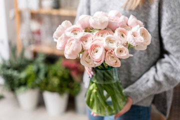 Persian buttercup in glass vases in womens hands. Bunch pale pink. the concept of a florist in a...