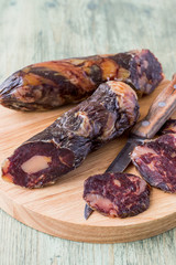 Horse sausage, sliced on a wooden cutting board.