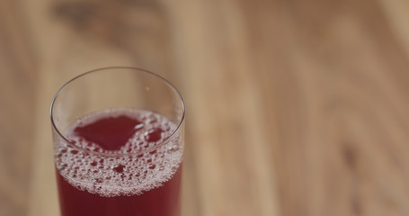 Closeup cranberry juice into the glass on wood table