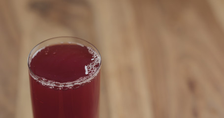 Closeup cranberry juice into the glass on wood table