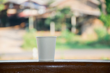 close up detail of paper coffee cup on wooden pillar with copyspace and green background