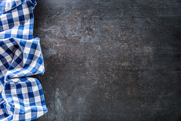 Top of view blue checkered tablecloth on dark concrete table.