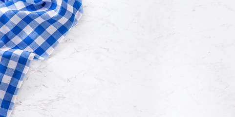 Top of view blue checkered tablecloth on white marble table.