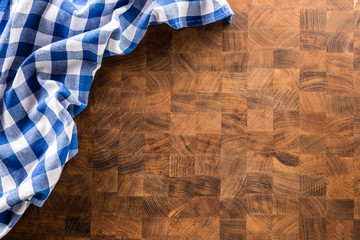 Top of view blue checkered tablecloth on wooden board.