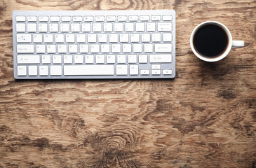 White computer keyboard and coffee on wooden desk. Business concept
