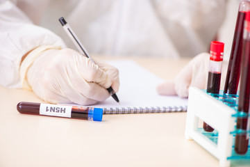 Young handsome lab assistant testing blood samples in hospital 