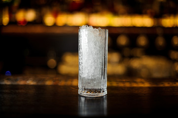 Thick-wall cocktail glass of crushed ice standing on the empty bar stand