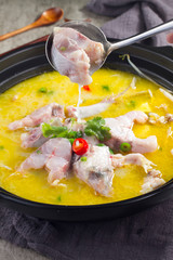 Boiled fish with pickled cabbage and chili in a black pot in a ceramic dish