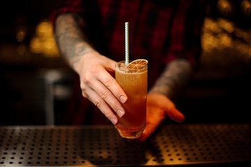 Fototapeta na wymiar Bartender serving a Singapore Sling cocktail with orange zest