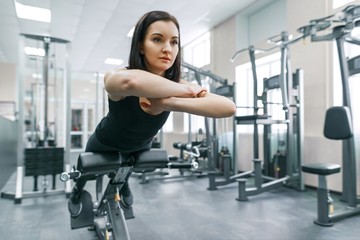 Young athletic woman exercising on the machines in modern sport gym. Fitness, sport, training, people, healthy lifestyle concept.