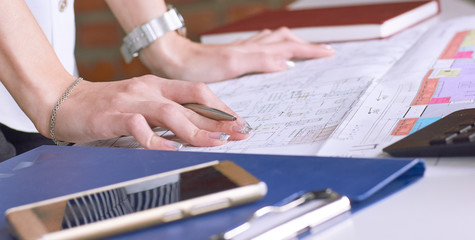 Real estate creative studio office. Architect woman working on architectural project for interior design. Woman's hands over the table with the drawing.