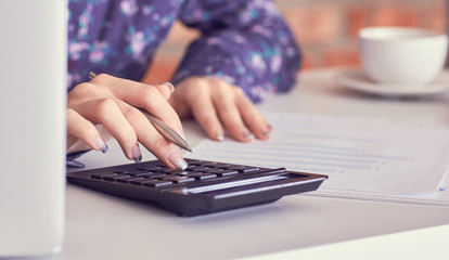 Close up of female accountant or banker hand making calculations. Savings, finances and economy concept