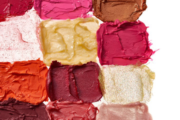 Smears of different colors are made with various lipstick isolated on a white background.