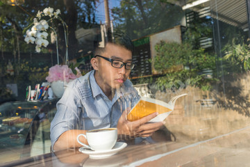 Fototapeta na wymiar Asian student focus on reading book at cafe