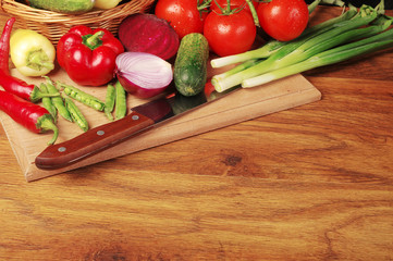 Vegetables on the kitchen board. Cabbage, tomatoes, radishes, cucumbers, carrots, peppers, eggplants, parsley on a wooden table