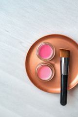 Makeup brush with blush pink and rouge color cream jars palette on stainless steel mixing plate - Make-up professional tool for artist. Top view background.