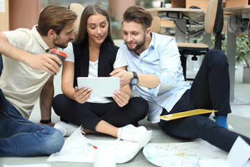Fototapeta premium Group of young business people and designers looking at project plan laid out on floor. They working on new project.