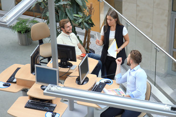 Top view of young modern colleagues in smart casual wear working together while spending time in the office.