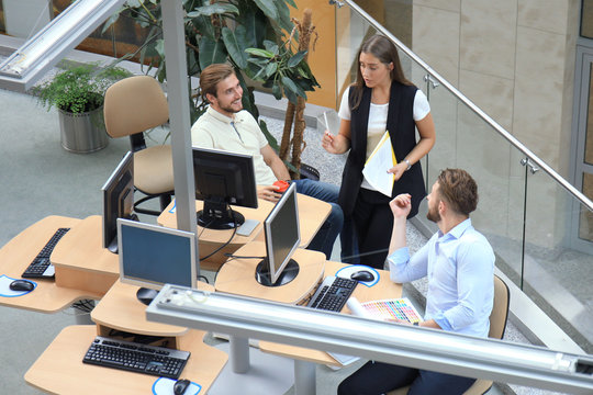 Top view of young modern colleagues in smart casual wear working together while spending time in the office.