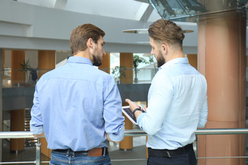 Young modern people in smart casual wear having a brainstorm meeting while standing in the creative office.