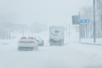 dangerous winter road conditions on a highway with oncoming traffic during heavy snowfall