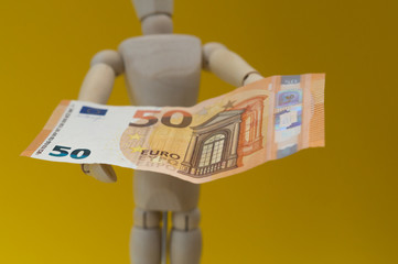Wooden mannequin holding a banknote with its hands. Economy.