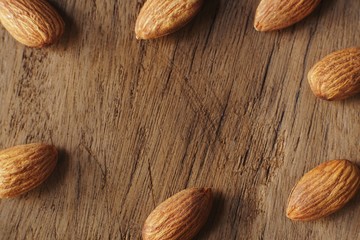 Almond nut in wooden bowl on wooden table with green leaf background