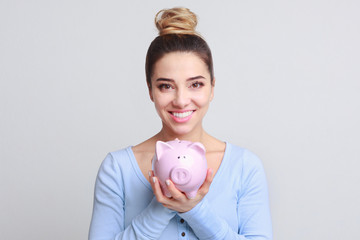 Fototapeta na wymiar Excited woman with piggy bank on background