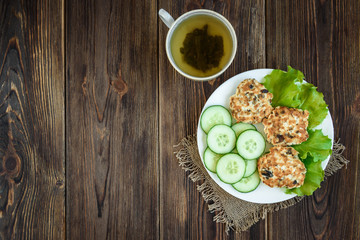 Homemade chicken and mushroom cutlets with salad, dill and cucumbers on dark wooden background. Healthy dinner or lunch.