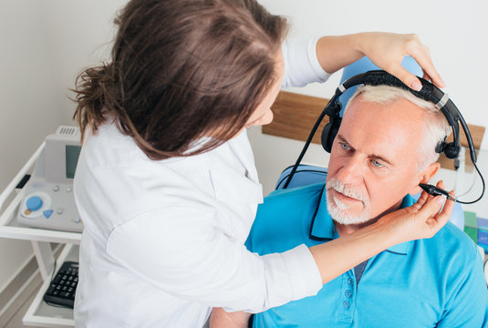 audiologist doing hearing test to a mature man at hearing clinic
