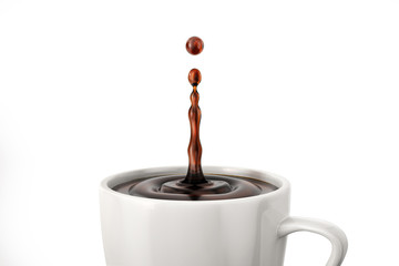 Single drop of coffee splashing into a white cup mug. Close up view.