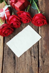 Group of lovely blooming red color rose flower on wood table background decorated with mini red heart figure, sweet valentine present concept