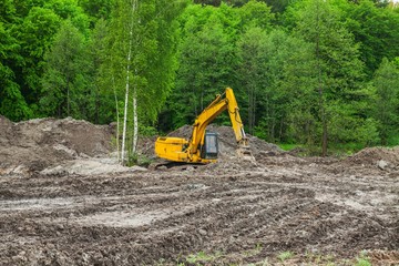 large yellow excavator working near forest.