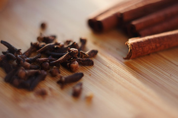 fragrant cloves and cinnamon lie on a wooden surface
