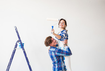 Renovation, redecoration and family concept - Young man holds young woman in his arms during renovation in apartment