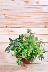 Fresh herb leaves variety in wood bowl on table