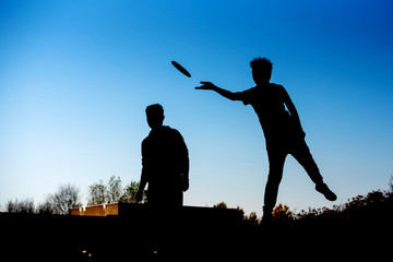 Silhouette of boy throwing frisbee playing disk golf