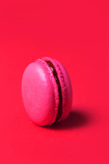 Close-up of pink sweet macaroon on red background, selective focus