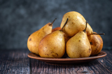 Fresh pears on a brown plate. Side view