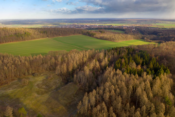View from the air over a deciduous forest in Northern Germany with a large meadow area switched on and a village in the background