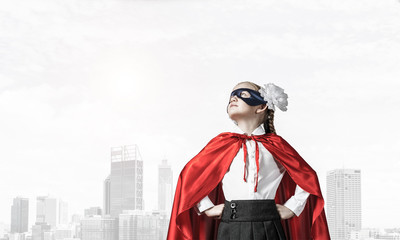Obraz premium Girl power concept with cute kid guardian against cityscape back