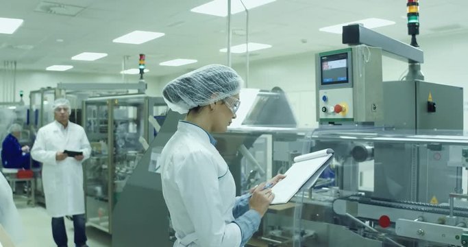Speсialists technician are monitoring the process on medicine factory.